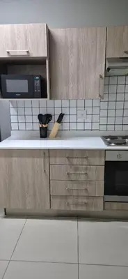 a kitchen with wooden cabinets and a counter top at Classy 2 bedroom in Halfway Gardens in Midrand