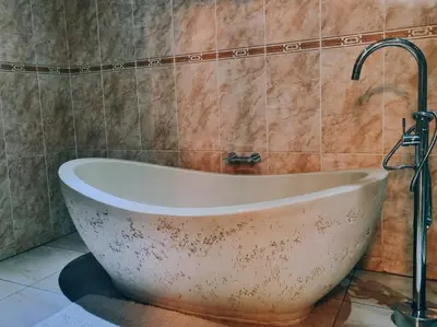 a bath tub with a faucet in a bathroom at Red Apple Guest House in Pretoria