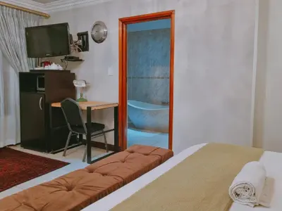 a bedroom with a bed and a desk and a mirror at Red Apple Guest House in Pretoria