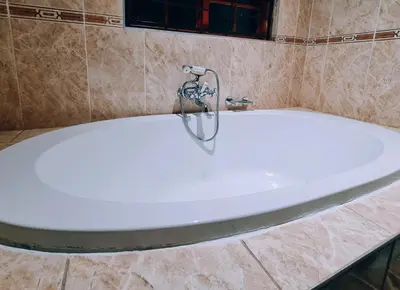 a bath tub with a faucet in a bathroom at Red Apple Guest House in Pretoria