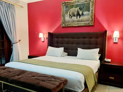 a bedroom with a large bed with a red wall at Red Apple Guest House in Pretoria