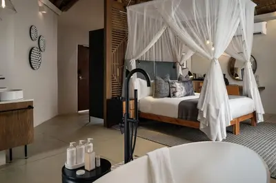 a bedroom with a bed and a tub in a room at Leopard Sands Kruger Park in Skukuza
