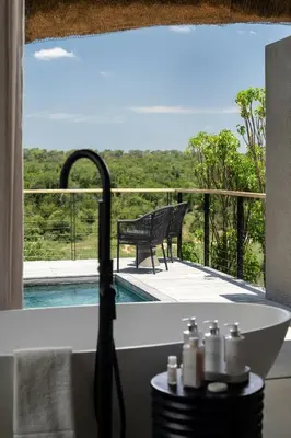 a bath tub in a bathroom with a view at Leopard Sands Kruger Park in Skukuza
