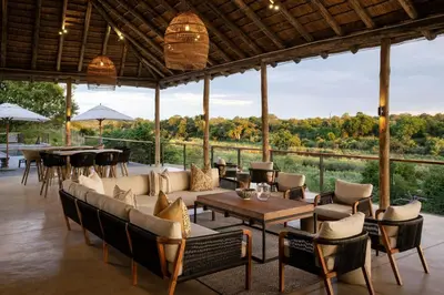 a restaurant with tables and chairs and a large window at Leopard Sands Kruger Park in Skukuza
