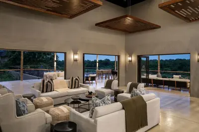 a living room with white furniture and large windows at Leopard Sands Kruger Park in Skukuza
