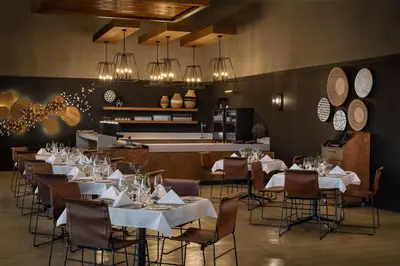 a restaurant with white tables and chairs and chandeliers at Leopard Sands Kruger Park in Skukuza
