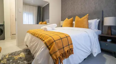 a bedroom with a large bed with a yellow blanket on it at Modern Midrand Gem in Midrand