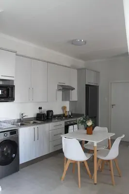 a white kitchen with a table and chairs and a stove at Nid de Rêve Accommodation in Midrand