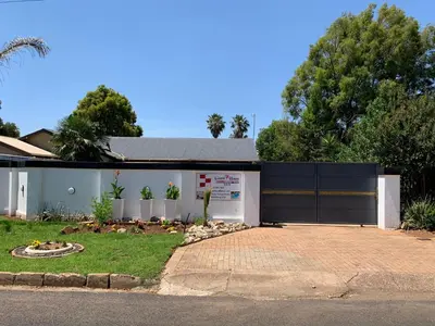 a white house with a gate and a driveway at TnB Guesthouse in Middelburg