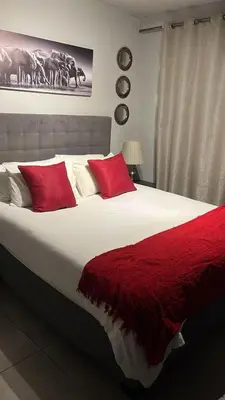 a bedroom with a large bed with red pillows at Circa unit 91 in Pretoria