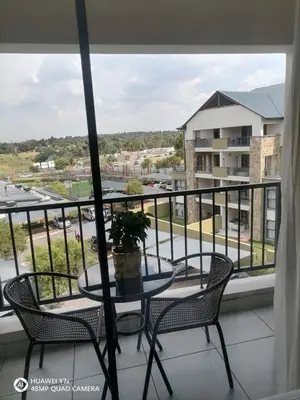 a balcony with a table and chairs and a view of a parking lot at URlyfstyle Apex Executive 8min to Mall of Africa in Midrand