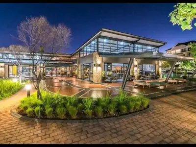 a large building with a basketball court in front of it at URlyfstyle Apex Executive 8min to Mall of Africa in Midrand