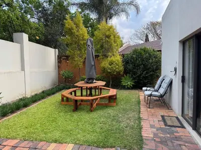a patio with a table with an umbrella and a chair at De Vlei - Private Accommodation in Garsfontein in Pretoria