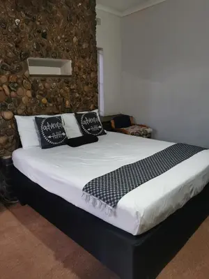 a bed with black and white pillows on it at GLESTER GUEST HOUSE in Pretoria