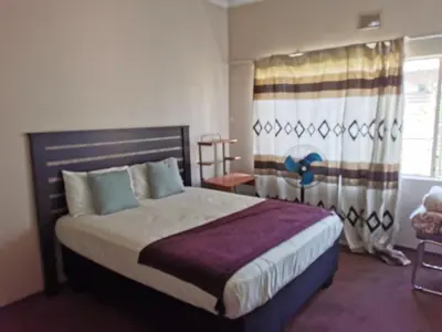 a bedroom with a large bed and a window at GLESTER GUEST HOUSE in Pretoria