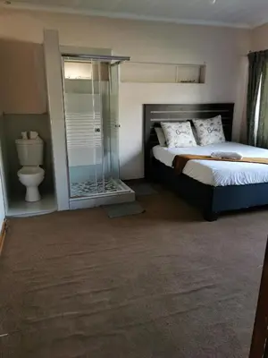 a bedroom with a bed and a glass shower at GLESTER GUEST HOUSE in Pretoria