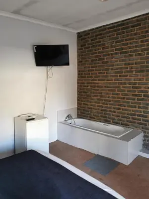 a bath tub in a room with a brick wall at GLESTER GUEST HOUSE in Pretoria