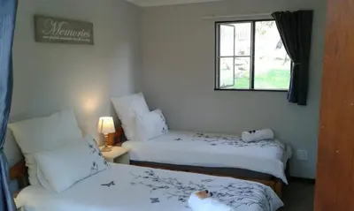 a room with two beds and a window at Blyde River Cabins in Hoedspruit