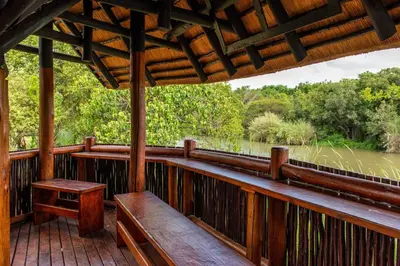 a wooden porch with benches and a view of a river at Kruger Park Lodge Unit No. 253 in Hazyview