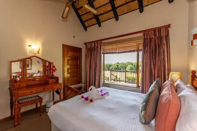 a bedroom with a bed and a desk and a window at Kruger Park Lodge Unit No. 516 in Hazyview