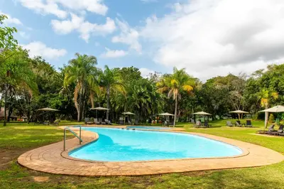 a swimming pool in a park with palm trees at Kruger Park Lodge Unit No. 516 in Hazyview