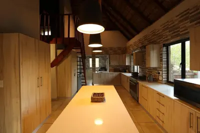 a large kitchen with wooden cabinets and a long table at Shiandi Villa in Hoedspruit