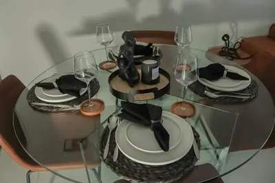 a glass table with plates and wine glasses on it at ELcaro Luxury Villas-The Cave in Midrand