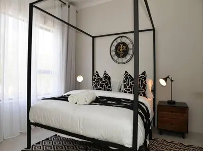 a bedroom with a black and white canopy bed with a clock at ELcaro Luxury Villas-The Cave in Midrand