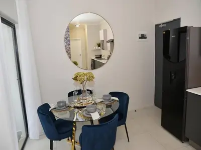 a dining room with a table with blue chairs and a mirror at Elcaro Luxury Villas-Royal Abode in Midrand