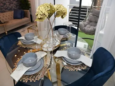 a dining room table with blue chairs and a table with plates and dishes at Elcaro Luxury Villas-Royal Abode in Midrand