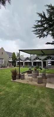 a picnic shelter with benches in a park at Bo Kamer Guesthouse in Ermelo