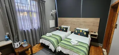 a bedroom with two beds and a window at Bo Kamer Guesthouse in Ermelo