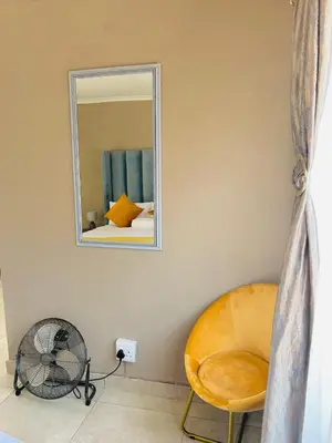 a room with a mirror and a chair and a fan at SERENE ACCOMMODATION PALACE in Bela-Bela