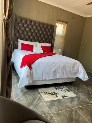 a bedroom with a large bed with red pillows at SERENE ACCOMMODATION PALACE in Bela-Bela
