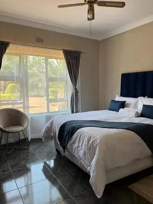 a bedroom with a bed and a chair and a window at SERENE ACCOMMODATION PALACE in Bela-Bela
