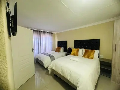 a bedroom with two beds and a door to a room at MBT Guesthouses in Ga-Mothiba