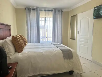 a bedroom with a large bed and a window at MBT Guesthouses in Ga-Mothiba