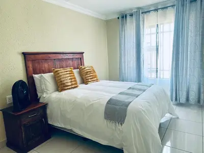 a bedroom with a large bed with pillows and a window at MBT Guesthouses in Ga-Mothiba