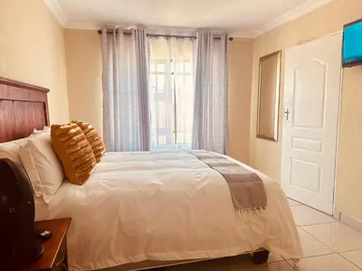 a bedroom with a white bed with a window at MBT Guesthouses in Ga-Mothiba