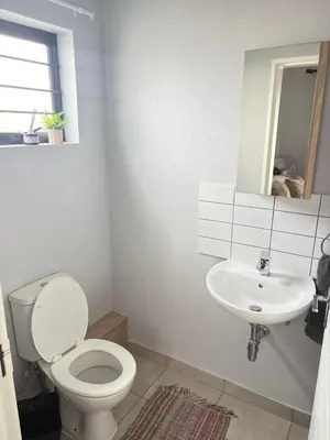 a white bathroom with a toilet and a sink at Monochrome View in Nelspruit