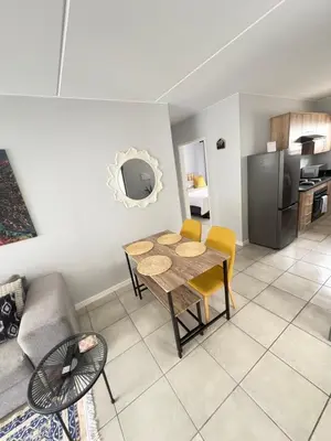 a living room with a table and a kitchen at Monochrome View in Nelspruit