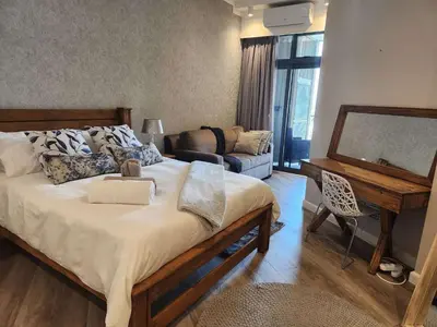 a bedroom with a large bed and a living room at Menlyn Maine Residences 721 in Pretoria