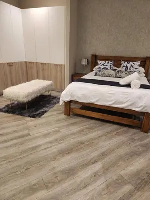 a bedroom with a bed and a wooden floor at Menlyn Maine Residences 721 in Pretoria