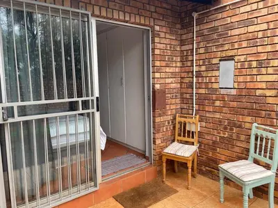 a patio with a door and two chairs on a brick wall at Magalies House in Pretoria
