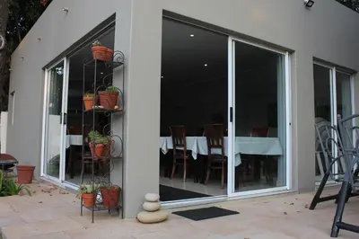 a conservatory with sliding glass doors with a table at Richtershuyz Luxury Accommodation in Pretoria