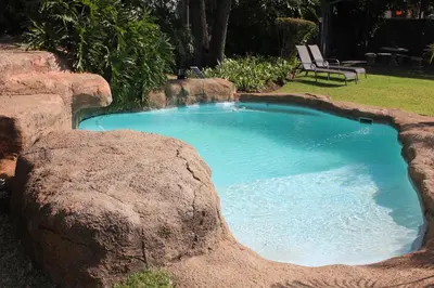 a large swimming pool with a large rock at Richtershuyz Luxury Accommodation in Pretoria