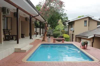 a person standing in a swimming pool next to a house at Tzaneen Guest House in Tzaneen