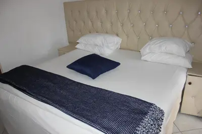 a bed with a blue blanket and two pillows at Tzaneen Guest House in Tzaneen