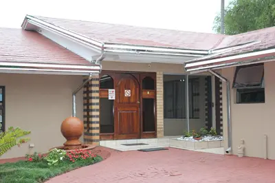 a home with a wooden door and a porch at Tzaneen Guest House in Tzaneen