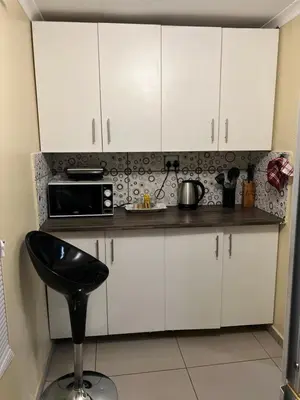 a kitchen with white cabinets and a black chair at MorningMist Boutique Sun in Centurion